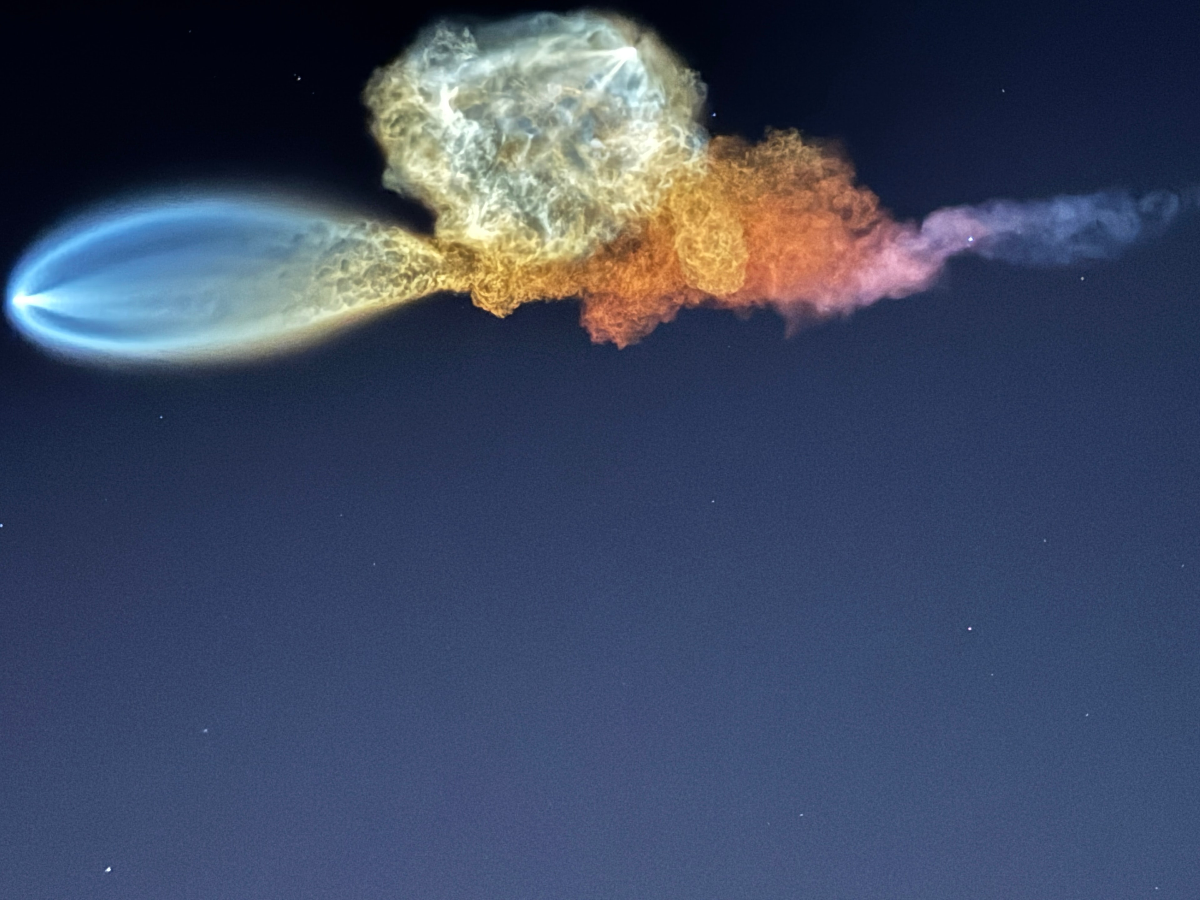 SpaceX rocket with blue and golden exhaust plumes against a dark night sky
