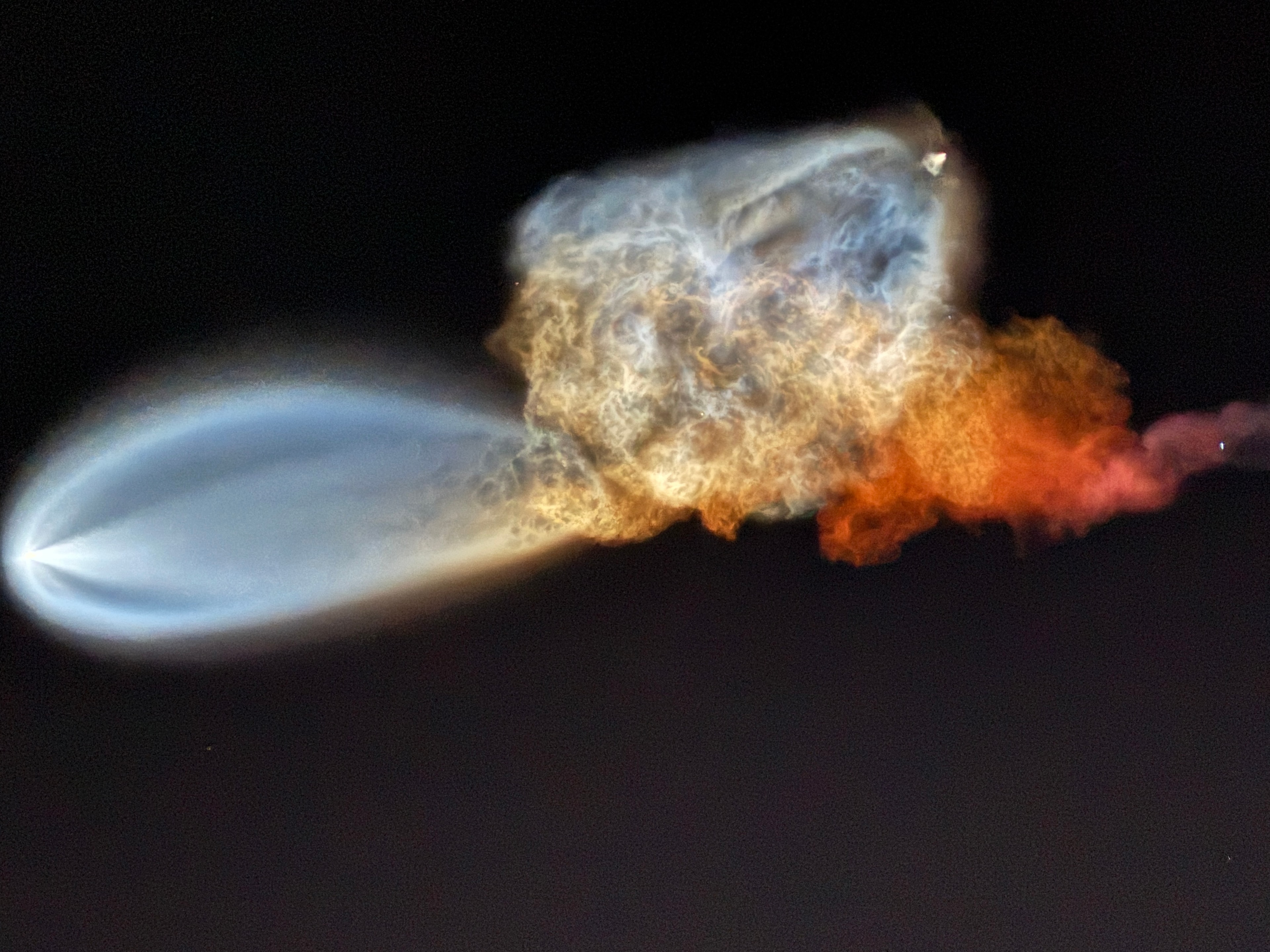 Rocket engine exhaust cloud with blue and orange glow against black sky
